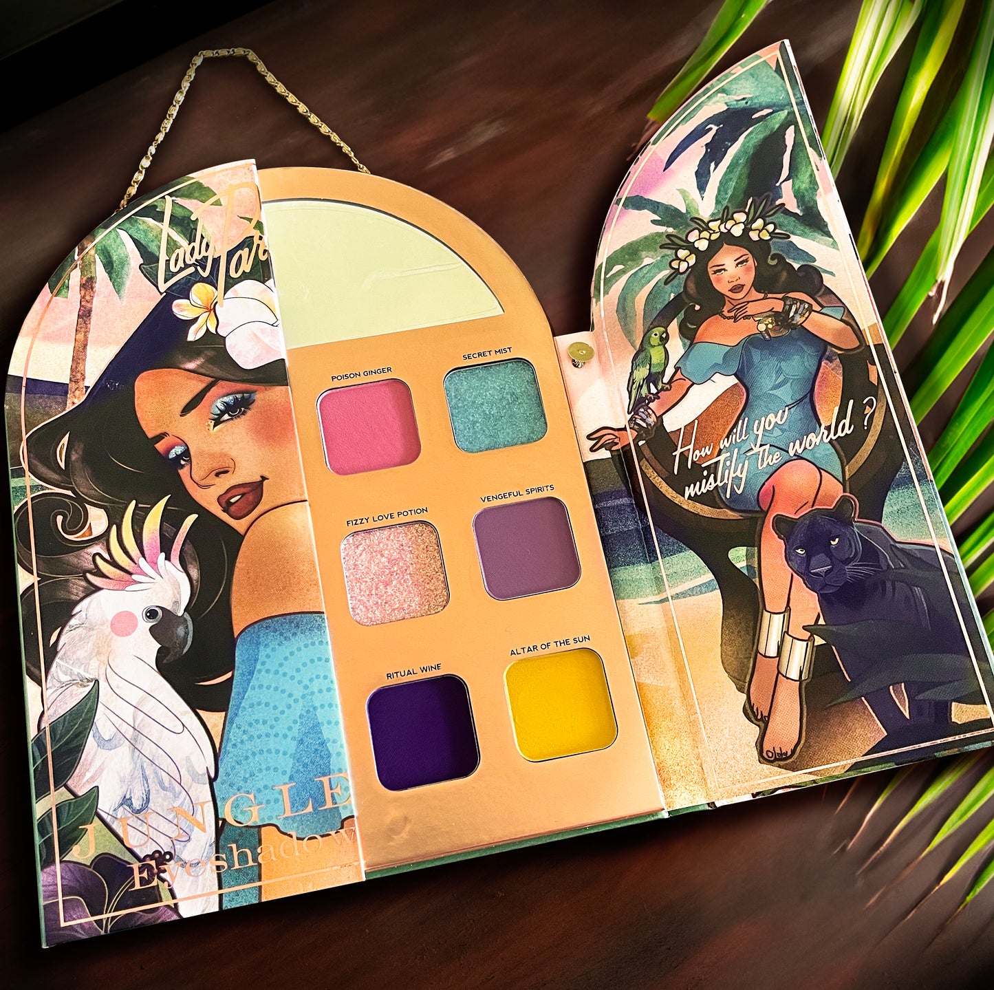 Tropical inspired eyeshadow palette viewed from above showing the selection of colors, inside mirror and artwork included inside. 